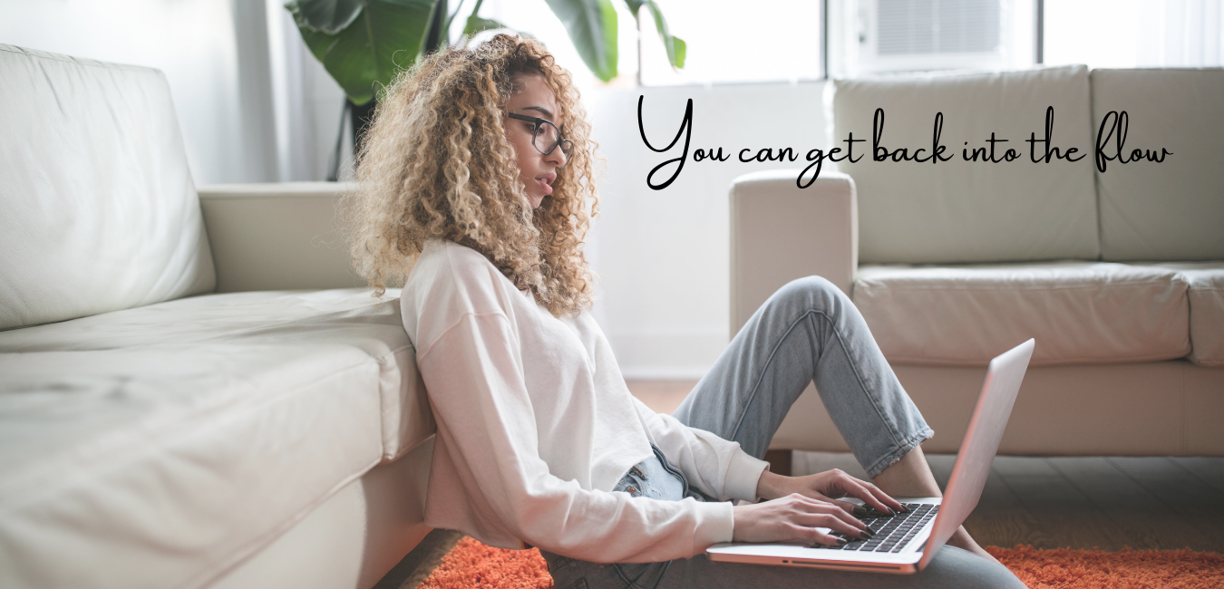 Young woman with glasses sitting on the floor in front of her couch typing on a laptop. The caption reads: "You can get back into the flow."